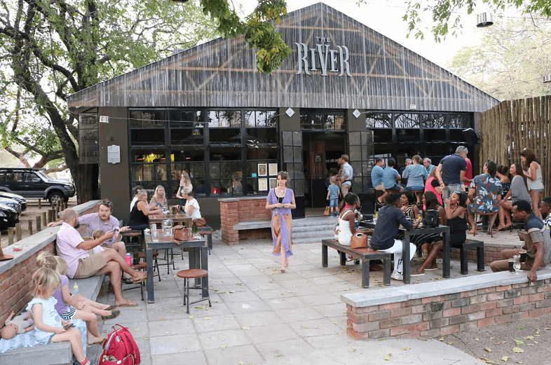 People relaxing, drinking and eating outside The River Brewing Company.