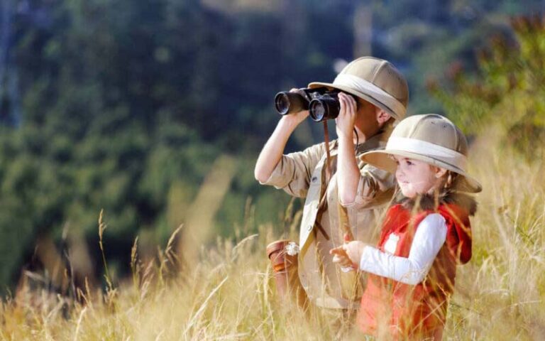 Two kids looking through binoculars while on safari