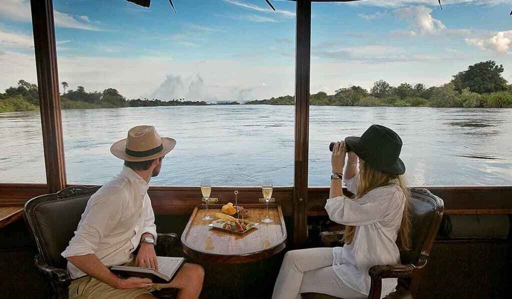 Two people enjoying snacks and drinks on a sunset cruise on the Zambezi River in Victoria Falls